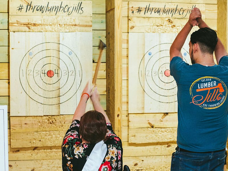 people throwing axes at indoor targets