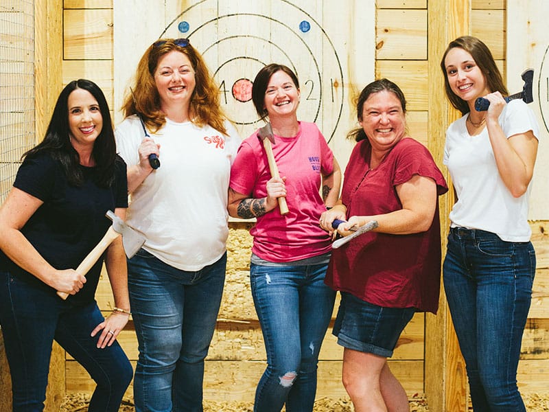 friends posing at an indoor axe throwing lane
