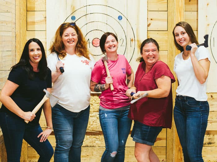 friends posing at an indoor axe throwing lane